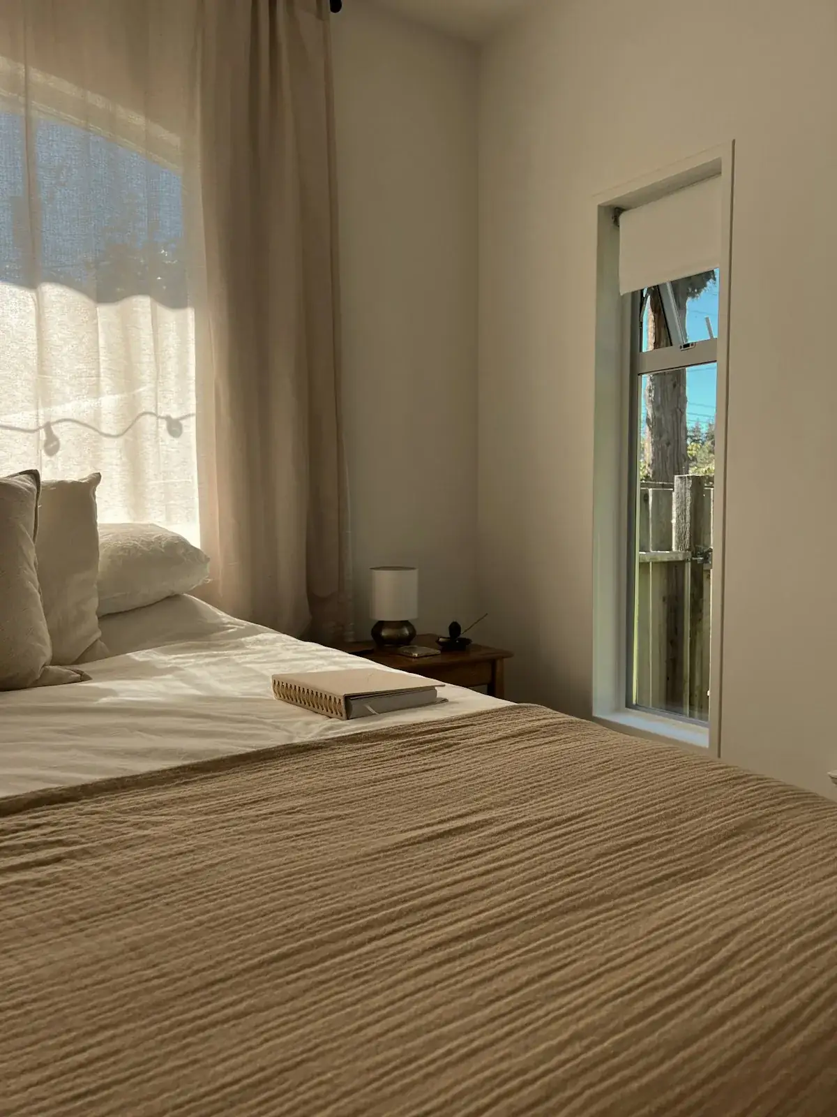 A cozy bedroom with soft linens and natural light streaming through the window.